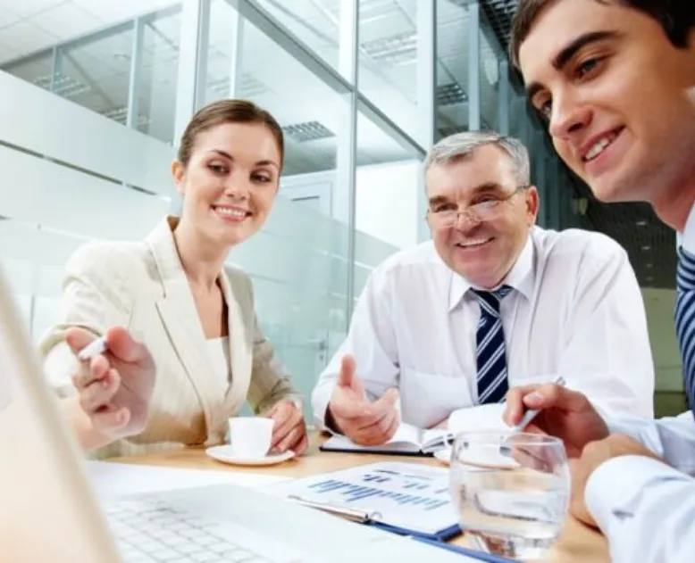 Equipe do escritório reunida com clientes em volta da mesa de trabalho